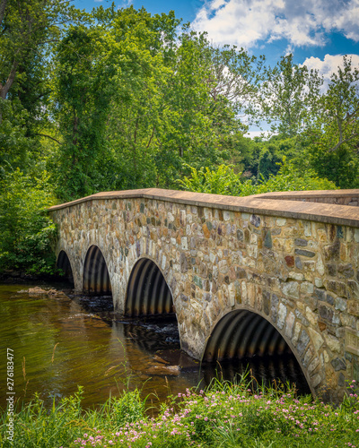 Foto Old stone bridge spanning a calmly flowing river on a sunny summer day