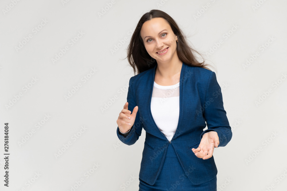Portrait to the waist a young pretty brunette manager woman of 30 years in a business blue suit with beautiful dark hair. Standing on a white background, talking, showing hands, with emotions. Portrait to the waist a young pretty brunette manager woman of 30 years in a business blue suit with beautiful dark hair. Standing on a white background, talking, showing hands, with emotions.