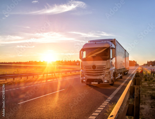Modern wagon truck transports cargo against the backdrop of a sunset. The concept of truck drivers in the field of freight and logistics, copy space