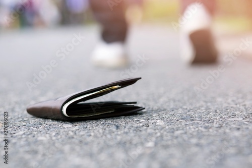  Men lose leather purse with money on the street. Closeup of wallet on the sidewalk road
