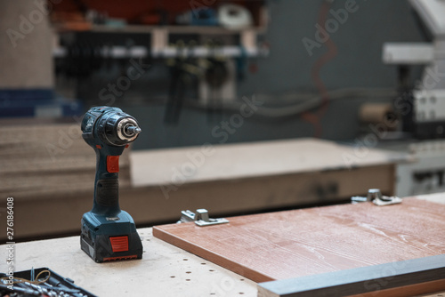 Drill on wooden table in carpenter`s workshop.