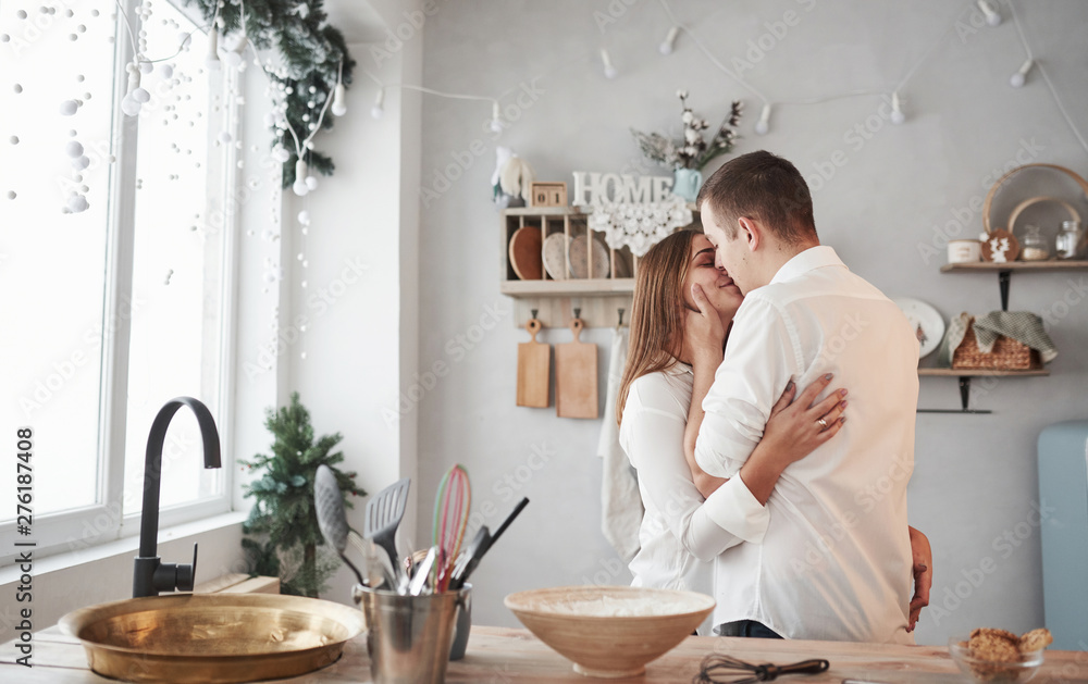 © standret - Cozy home atmosphere. Happy couple kissing in the kitchen. Having nice weekend together
