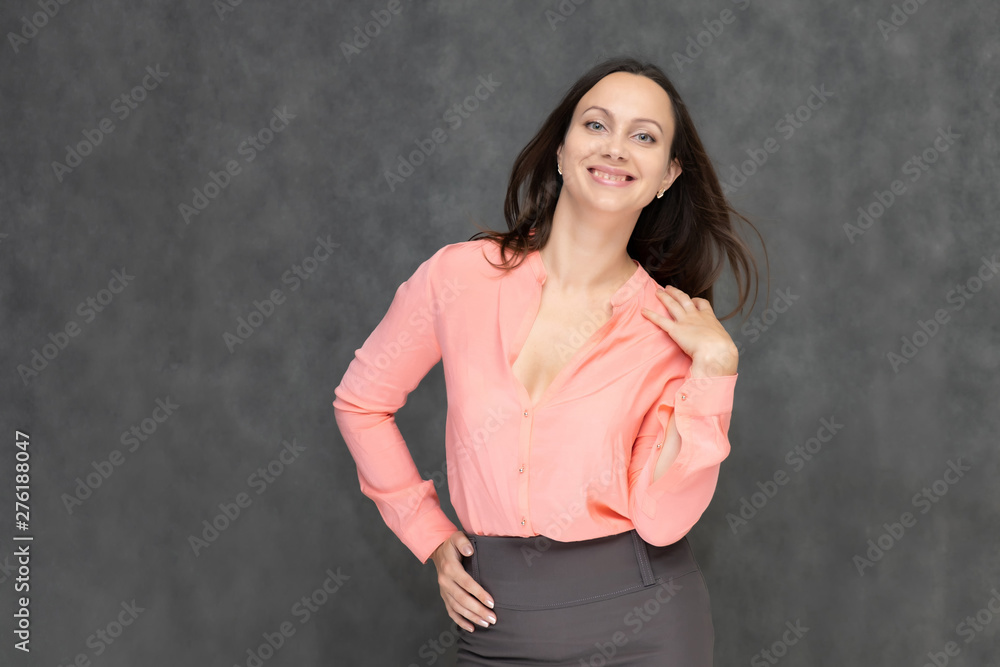 Portrait to the waist a young pretty brunette manager woman of 30 years in business clothes with beautiful dark hair. It is standing on a gray background, talking, showing hands, with emotions Portrait to the waist a young pretty brunette manager woman of 30 years in business clothes with beautiful dark hair. It is standing on a gray background, talking, showing hands, with emotions