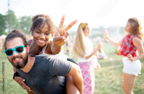 Portrait of multiethnic couple piggybacking at summer music festival