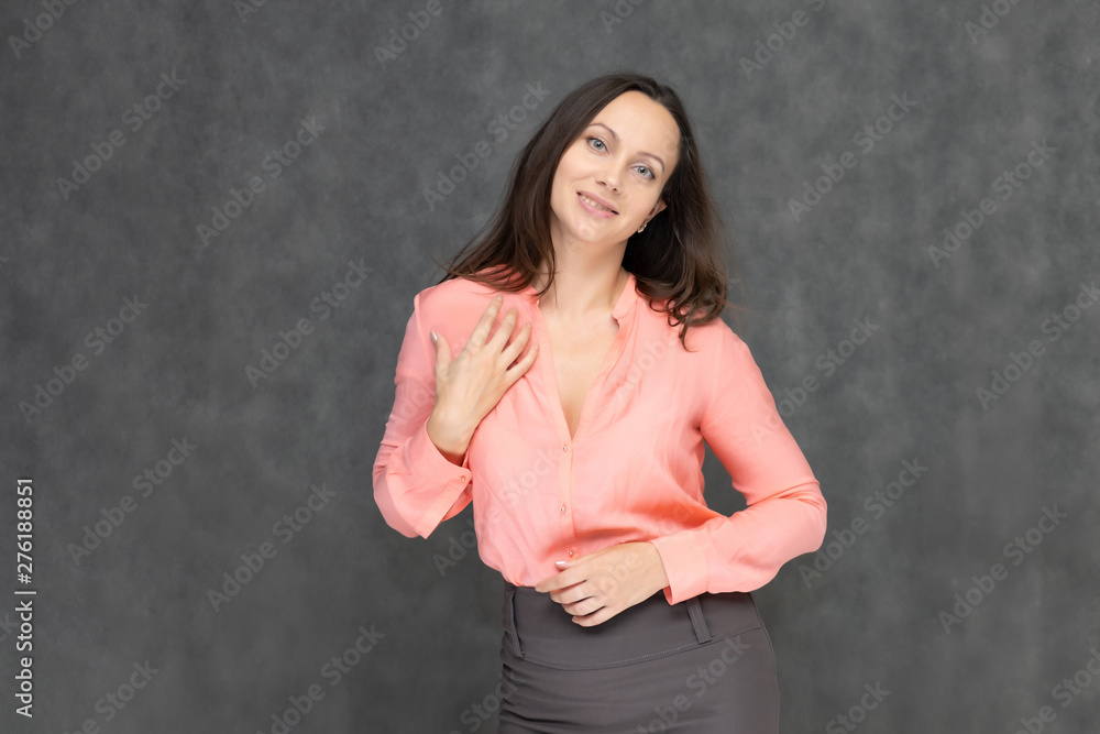 Portrait to the waist a young pretty brunette manager woman of 30 years in business clothes with beautiful dark hair. It is standing on a gray background, talking, showing hands, with emotions Portrait to the waist a young pretty brunette manager woman of 30 years in business clothes with beautiful dark hair. It is standing on a gray background, talking, showing hands, with emotions