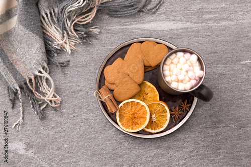 drinks and season concept - cup of hot chocolate with marshmallow, dried orange, heart shaped gingerbread cookies, cinnamon and anise on plate or tray and warm blanket