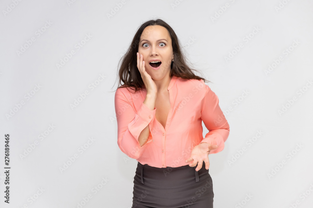 Portrait to the waist a young pretty brunette manager woman of 30 years in business clothes with beautiful dark hair. Standing on a white background, talking, showing hands, with emotions. Portrait to the waist a young pretty brunette manager woman of 30 years in business clothes with beautiful dark hair. Standing on a white background, talking, showing hands, with emotions.