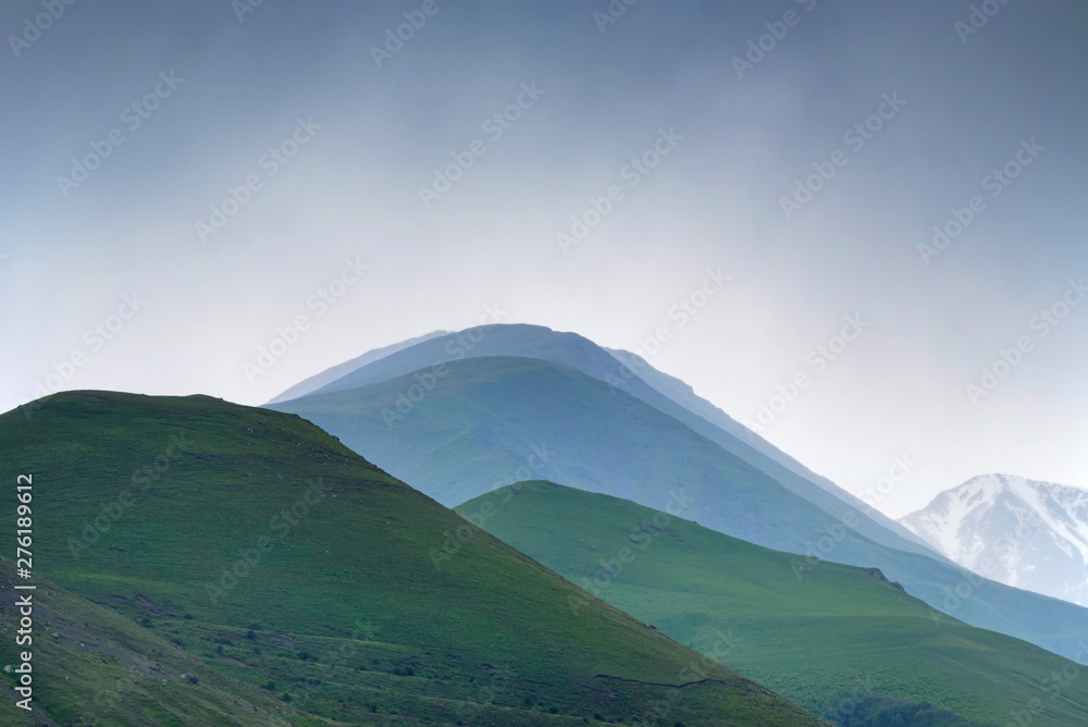 Fototapeta premium Scenic view of foggy mountains. Silhouettes in the evening