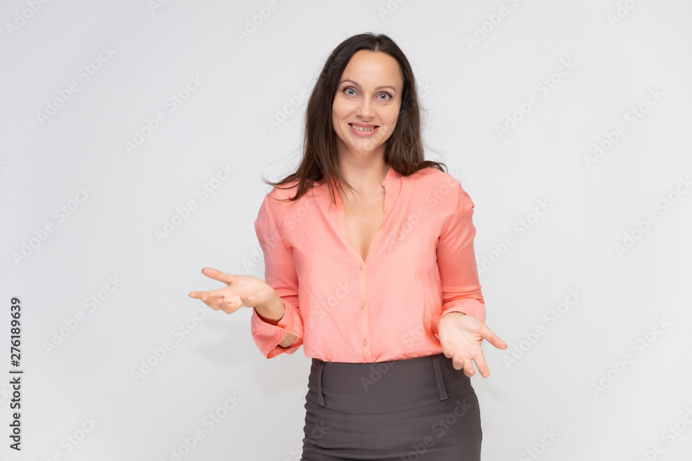 Portrait to the waist a young pretty brunette manager woman of 30 years in business clothes with beautiful dark hair. Standing on a white background, talking, showing hands, with emotions.