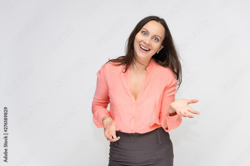 Portrait to the waist a young pretty brunette manager woman of 30 years in business clothes with beautiful dark hair. Standing on a white background, talking, showing hands, with emotions. Portrait to the waist a young pretty brunette manager woman of 30 years in business clothes with beautiful dark hair. Standing on a white background, talking, showing hands, with emotions.