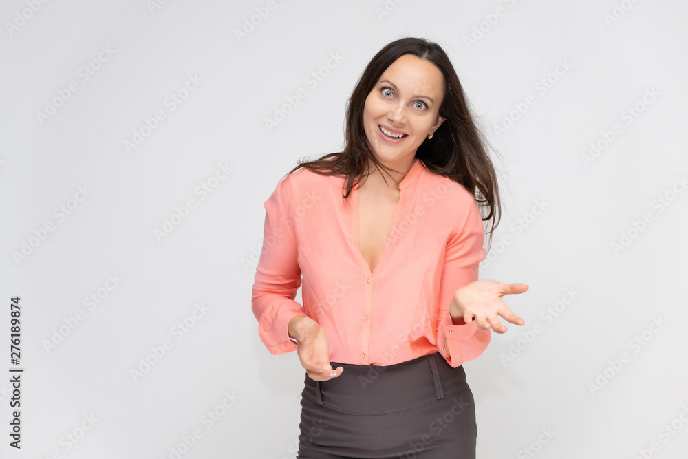 Portrait to the waist a young pretty brunette manager woman of 30 years in business clothes with beautiful dark hair. Standing on a white background, talking, showing hands, with emotions. Portrait to the waist a young pretty brunette manager woman of 30 years in business clothes with beautiful dark hair. Standing on a white background, talking, showing hands, with emotions.