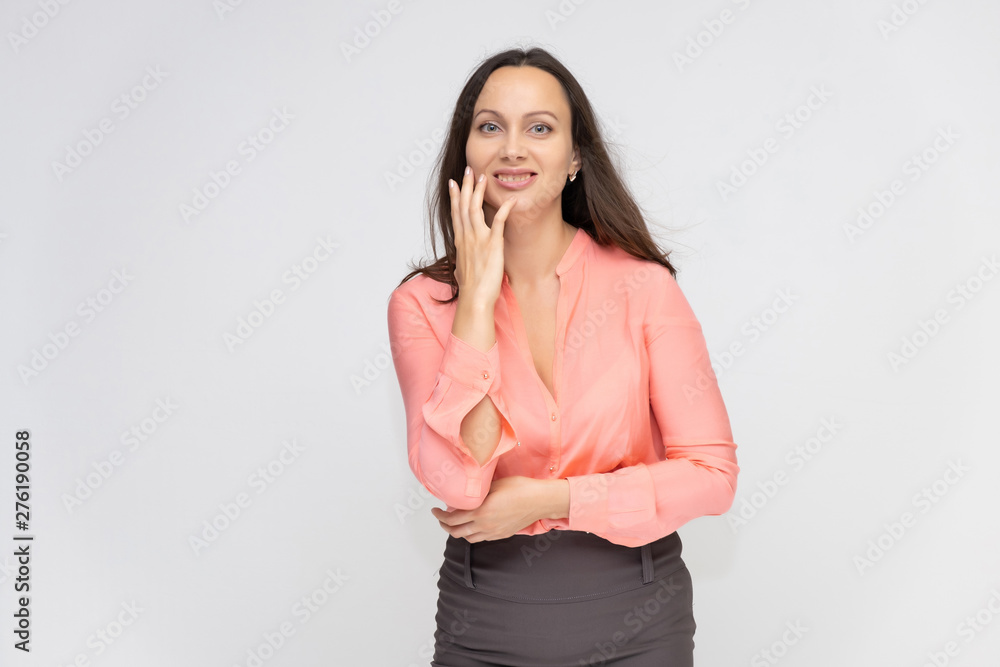 Portrait to the waist a young pretty brunette manager woman of 30 years in business clothes with beautiful dark hair. Standing on a white background, talking, showing hands, with emotions. Portrait to the waist a young pretty brunette manager woman of 30 years in business clothes with beautiful dark hair. Standing on a white background, talking, showing hands, with emotions.