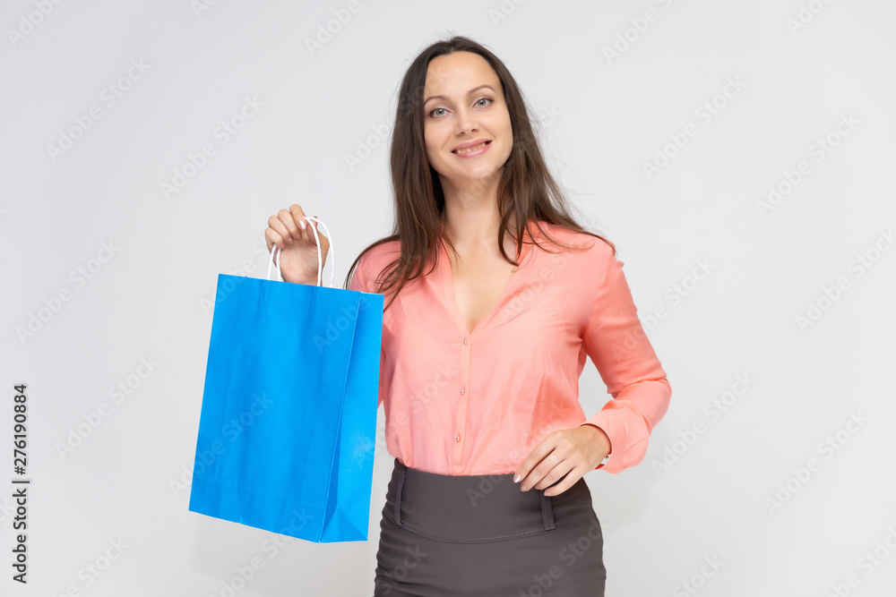 Portrait to the waist of a young pretty brunette woman of 30 years in business clothes with beautiful dark hair with a blue shopping bag. On a white background, talking, showing hands, with emotions Portrait to the waist of a young pretty brunette woman of 30 years in business clothes with beautiful dark hair with a blue shopping bag. On a white background, talking, showing hands, with emotions
