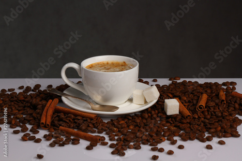 White coffee Cup, coffee beans and cinnamon on grey background