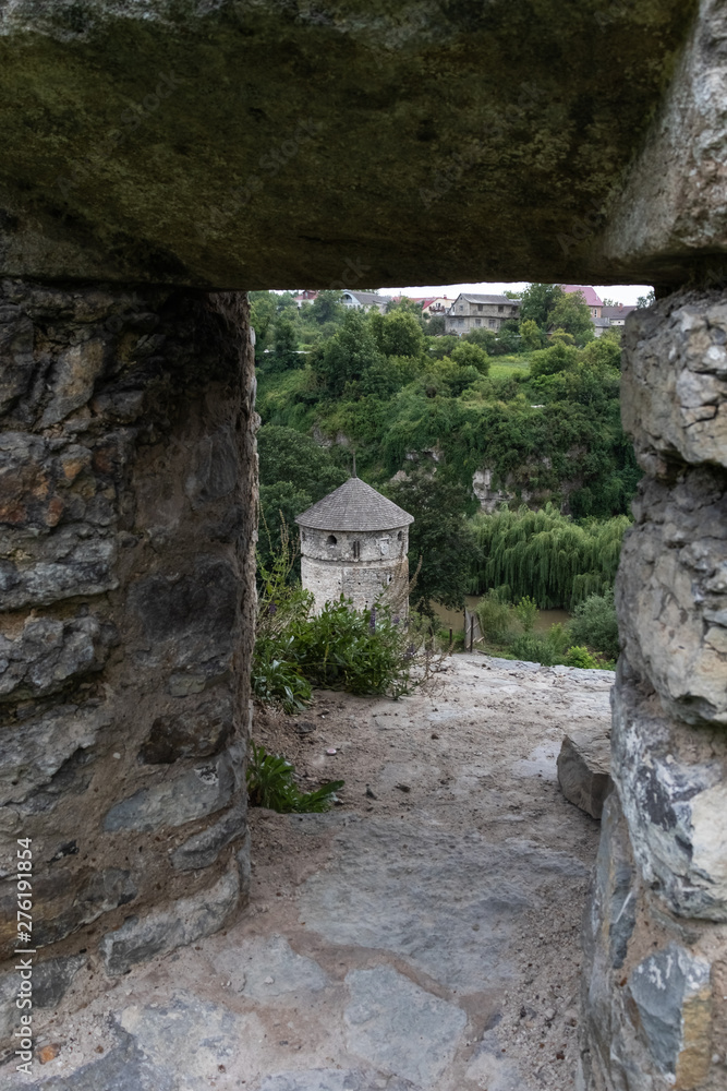 View of the medieval stone tower through the loophole in the stone wall. Complex of defensive buildings, XVI-XVIII centuries. Kamianets-Podilskyi, Ukraine.