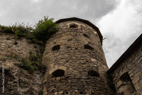 Medieval stone tower with loopholes against the background of a dark sky. Complex of defensive buildings, XVI-XVIII centuries. Kamianets-Podilskyi, Ukraine.