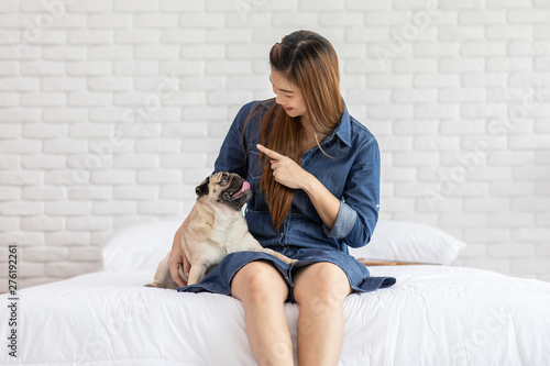 Beautiful Asian young woman playing with her dog and smile with dog pug breed looking in funny and serious face in bedroom feeling so happiness and relaxation,Dog Friendship Concept © 220 Selfmade studio