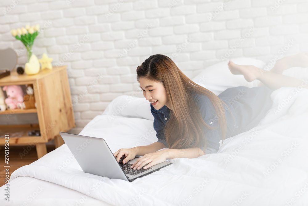 Beautiful Attractive Asian young woman lying on bed and using computer laptop for using social media and shopping online relax in bedroom in holiday,Lifestyle in bedroom Concept Beautiful Attractive Asian young woman lying on bed and using computer laptop for using social media and shopping online relax in bedroom in holiday,Lifestyle in bedroom Concept