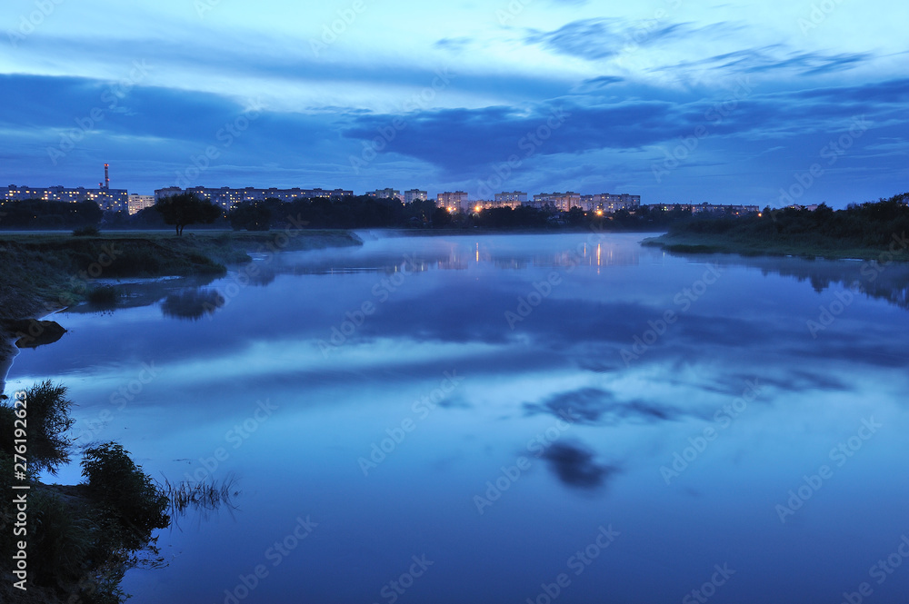 Night landscape with moonlight, wide river and reflection of the lights of the big city