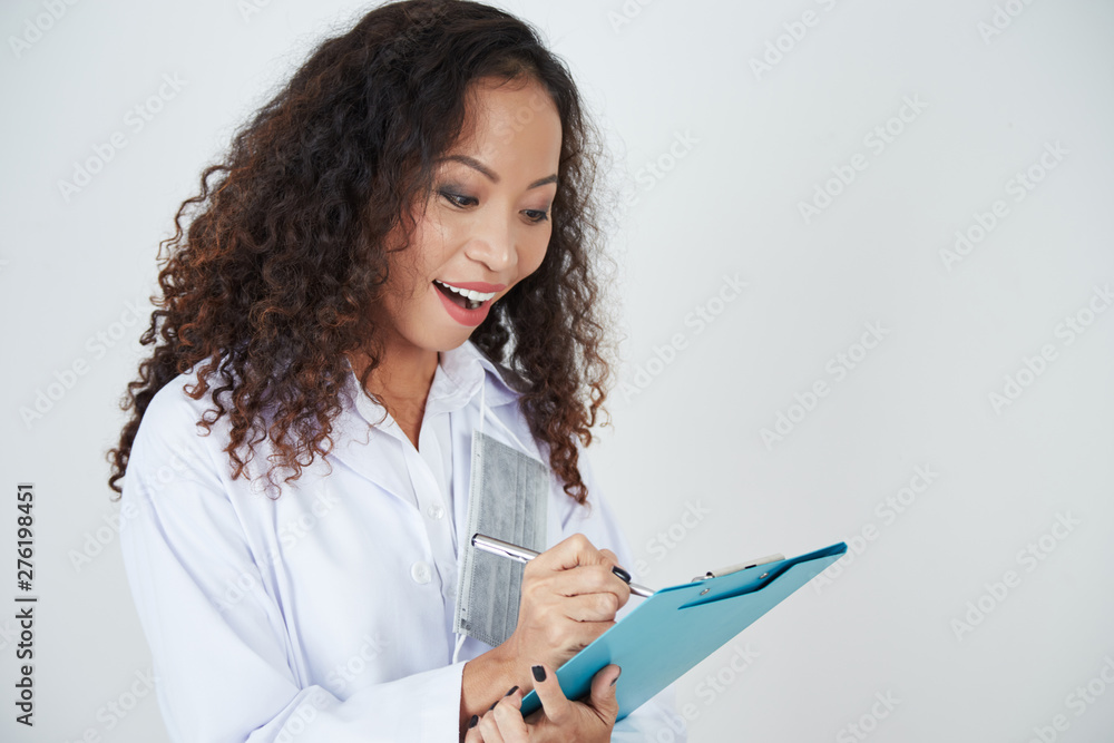 Cheerful excited female physician filling medical history of patient, isolated on white Cheerful excited female physician filling medical history of patient, isolated on white