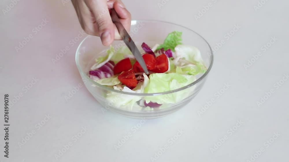 close up of hands chopping some tomatoes and putting them into a salad close up of hands chopping some tomatoes and putting them into a salad
