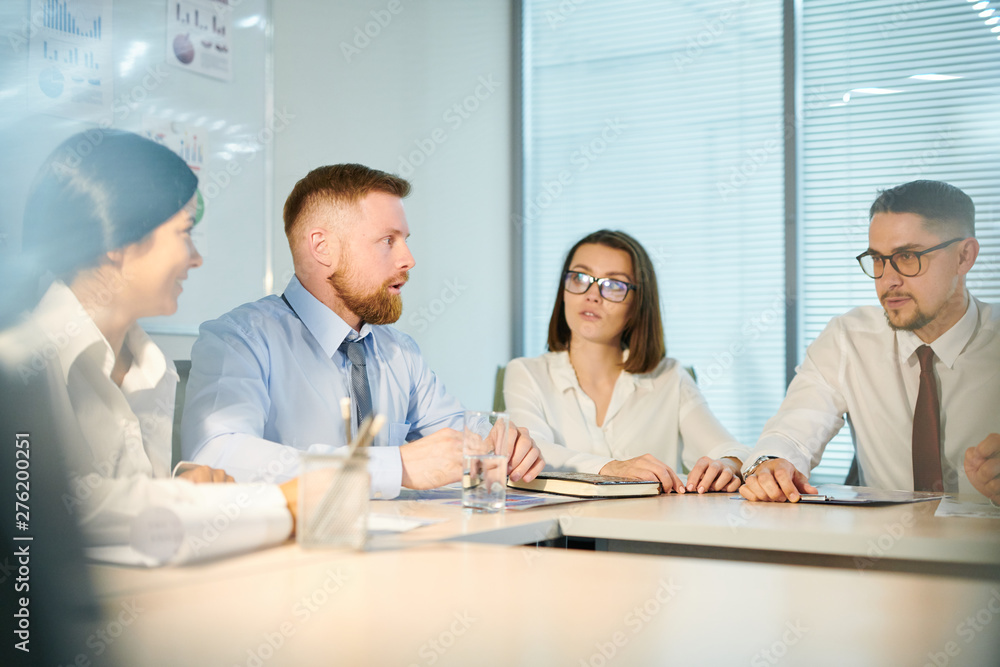 Obraz premium Four young colleagues preparing for conference in boardroom