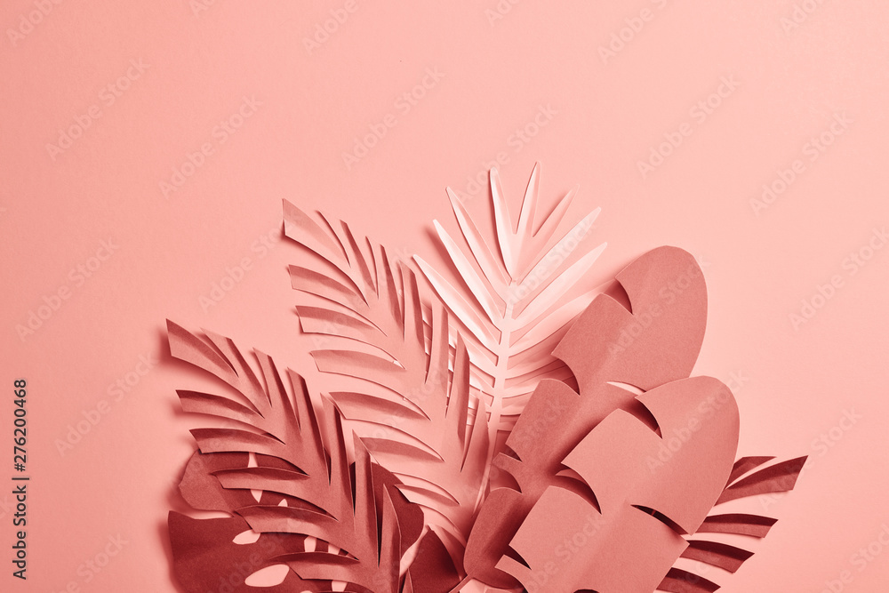 bunch of paper cut palm leaves on pink background