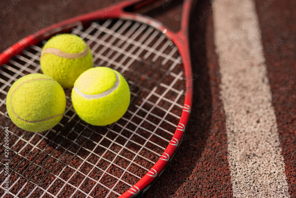 Three yellow tennis spheres lying on racket by white line