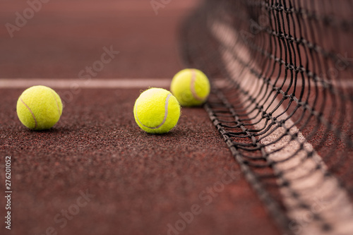 Three yellow tennis balls on court or playground and net