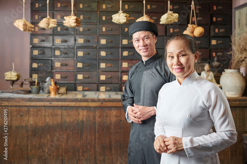 Fotografie Smiling mature Asian man and woman working at traditional old pharmacy