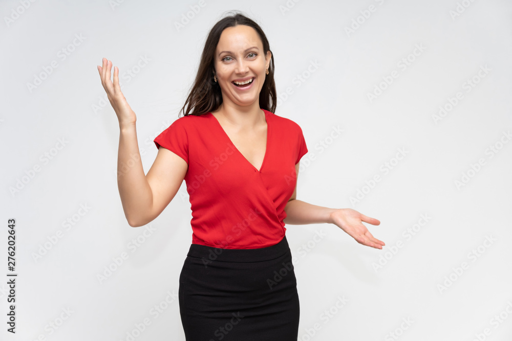 Portrait to the waist of a young pretty brunette woman of 30 years old in a bright red sweater with beautiful dark hair. Standing on a white background, talking, showing hands, with emotions Portrait to the waist of a young pretty brunette woman of 30 years old in a bright red sweater with beautiful dark hair. Standing on a white background, talking, showing hands, with emotions