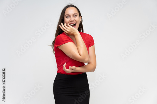 Portrait to the waist of a young pretty brunette woman of 30 years old in a bright red sweater with beautiful dark hair. Standing on a white background  talking  showing hands  with emotions