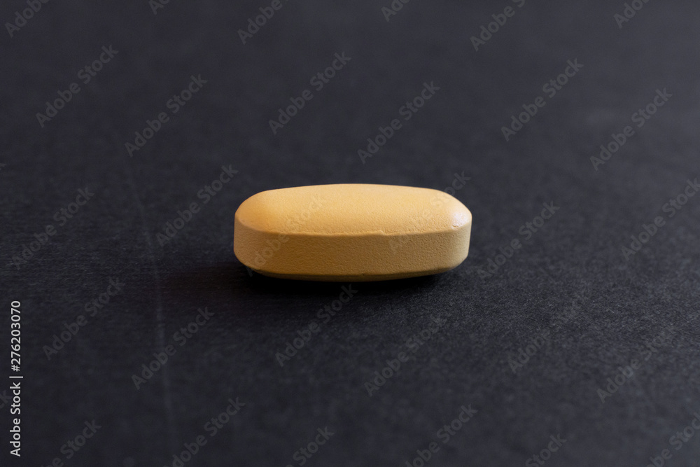 yellol pill, tablet isolated on dark / grey background yellol pill, tablet isolated on dark / grey background
