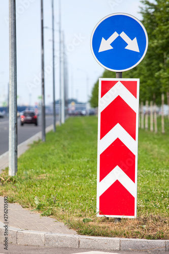 Road sign with two directions for driving, asphalt roadside at summer