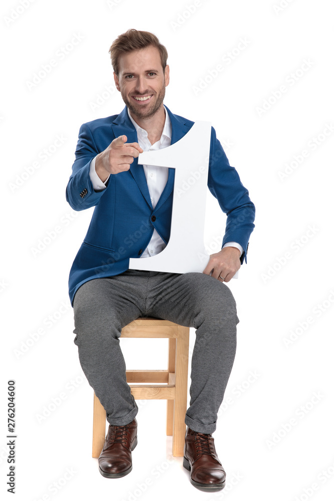 Casual guy pointing to camera and holding a number one Casual guy pointing to camera and holding a number one