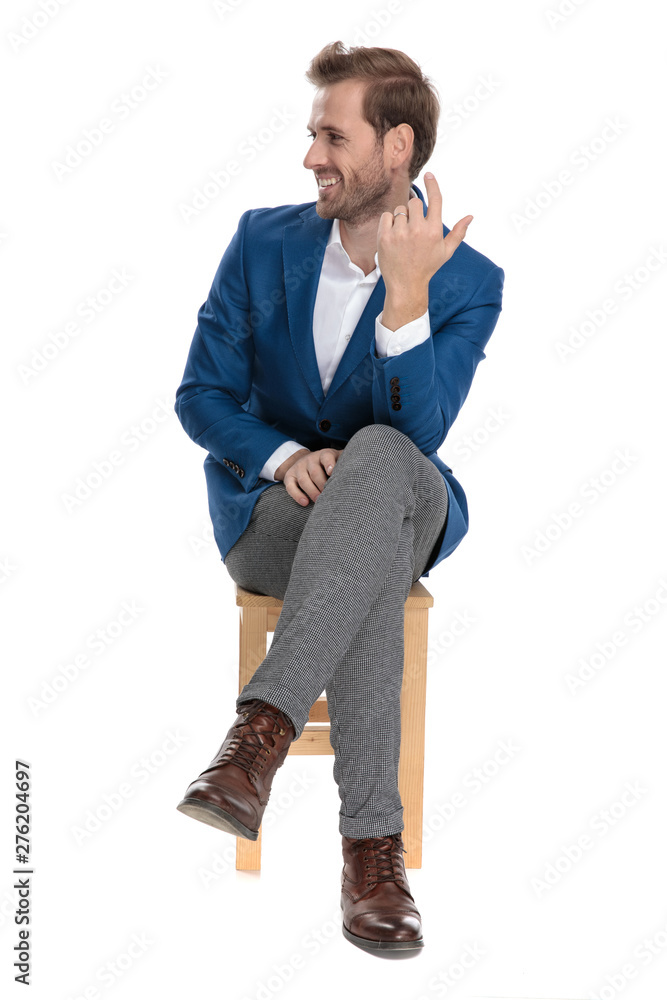 Jolly casual guy laughing to the side while sitting Jolly casual guy laughing to the side while sitting