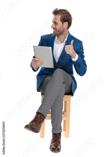 Casual guy giving a thumb up and holding his tablet