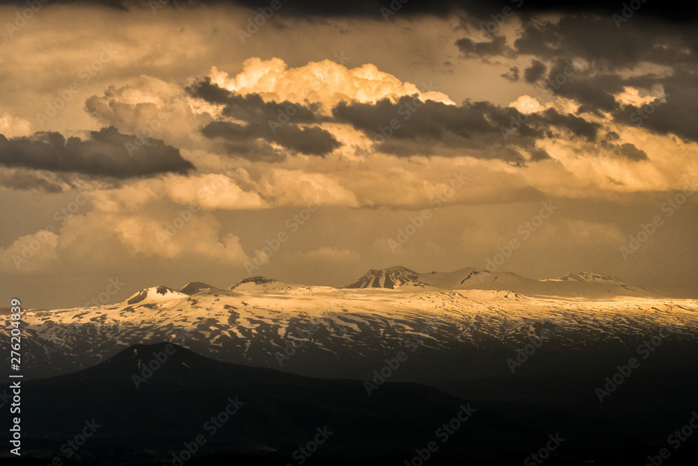 Silhouettes of mountains against the background of an orange sky. Sunset in the mountains. Geghama Mountains. Armenia