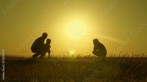 mom and dad play with their little daughter. happy child goes from father to mother. mother and Dad play with their daughter in sun. young family with child of 1 year. family happiness concept.