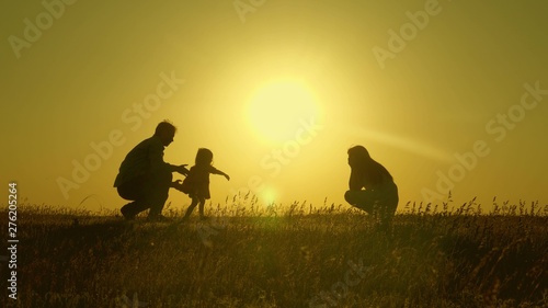 mom and dad play with their little daughter. happy child goes from father to mother. mother and Dad play with their daughter in sun. young family with child of 1 year. family happiness concept.
