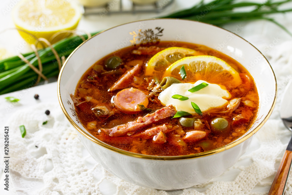 Traditional Russian soup Solyanka with meat, sausages, vegetables, capers, pickles and olives with lemon on wooden table. Rustic style. Traditional Russian soup Solyanka with meat, sausages, vegetables, capers, pickles and olives with lemon on wooden table. Rustic style.