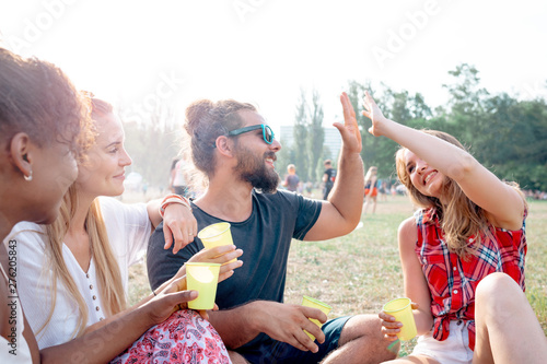 Friends at music festival sitting on grass and having fun