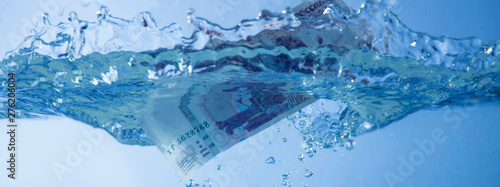 Money concept. Rubles sinking in water as symbol of financiall crisis and inflation.