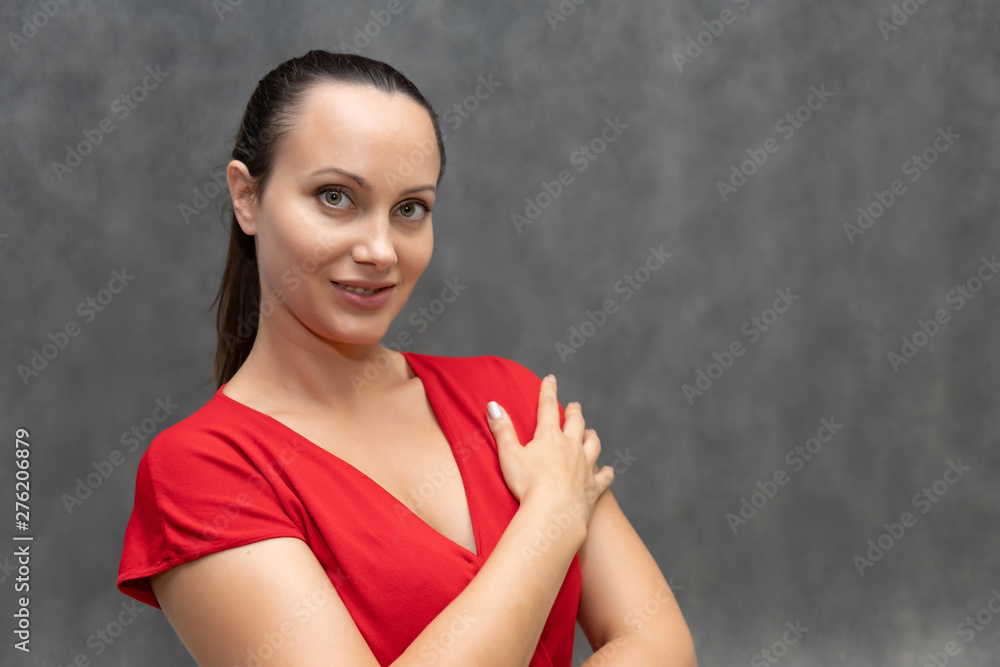 portrait of a young fashionable pretty brunette woman 30 years old with beautiful dark hair in a red sweater. On a gray background, smiling, showing emotions. portrait of a young fashionable pretty brunette woman 30 years old with beautiful dark hair in a red sweater. On a gray background, smiling, showing emotions.
