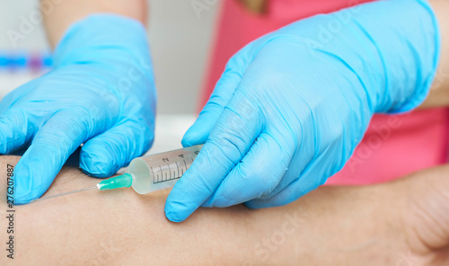 Nurse with a syringe in her hand is going to take a patient's blood sample for a blood test at the hospital.