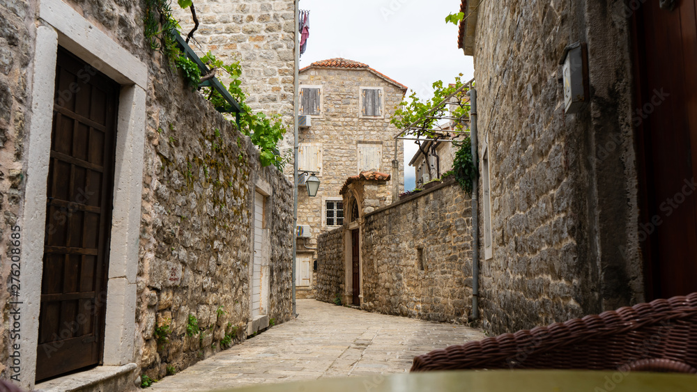 Narrow street with stone houses with vineyard. Budva citadel medieval town in Montenegro
