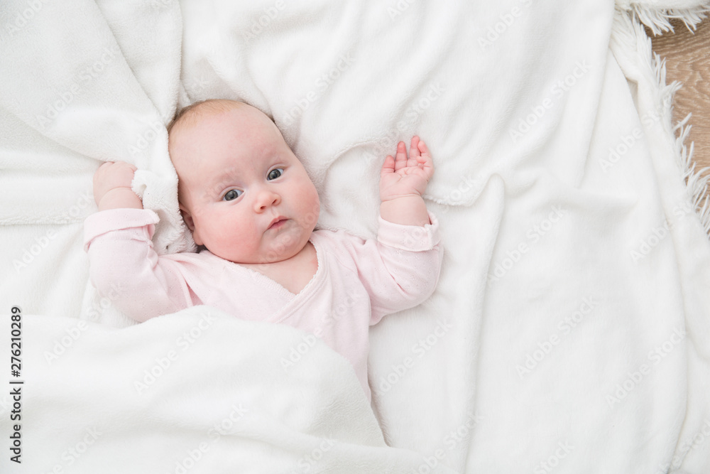 baby girl is lying on white blanket