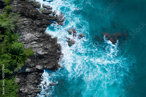 Aerial drone top view of ocean's beautiful waves crashing on the rocky island coast