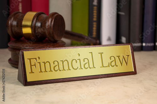 Golden sign with gavel and law books on a desk with financial law