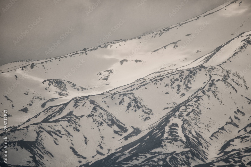 A steep slope of a rocky mountain covered with snow. Armenia